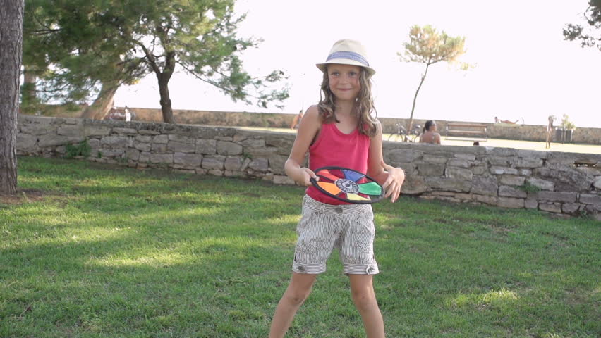 Slow Motion Shot Of A Young Girl Throwing A Colourful Frisbee Into Camera. She
