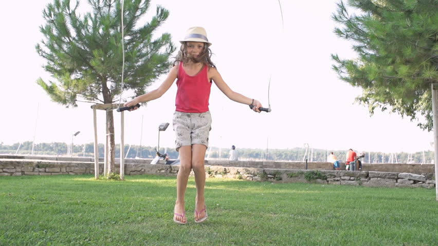 Slow Motion Shot Of A Cute Girl Wearing A Fashion Hat And Jumping Rope Outdoors.