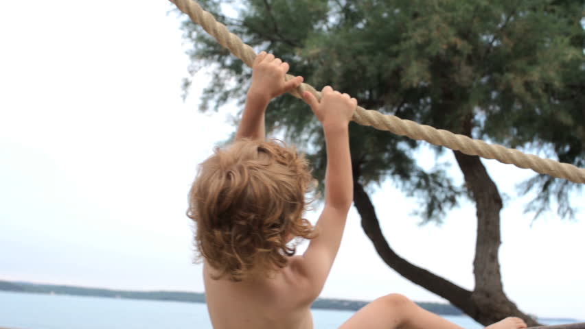 Slow Motion Shot Of A Sporty Boy With Red Curly Hair Jumping Off The Rope Swing