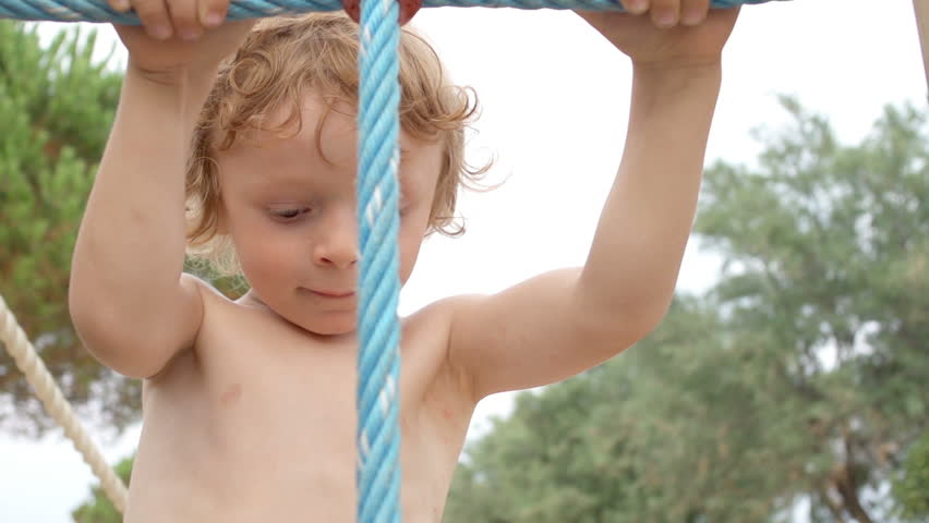 Slow Motion Close Shot Of A Cute Young Boy Climbing Up A Rope Ladder In Outdoor