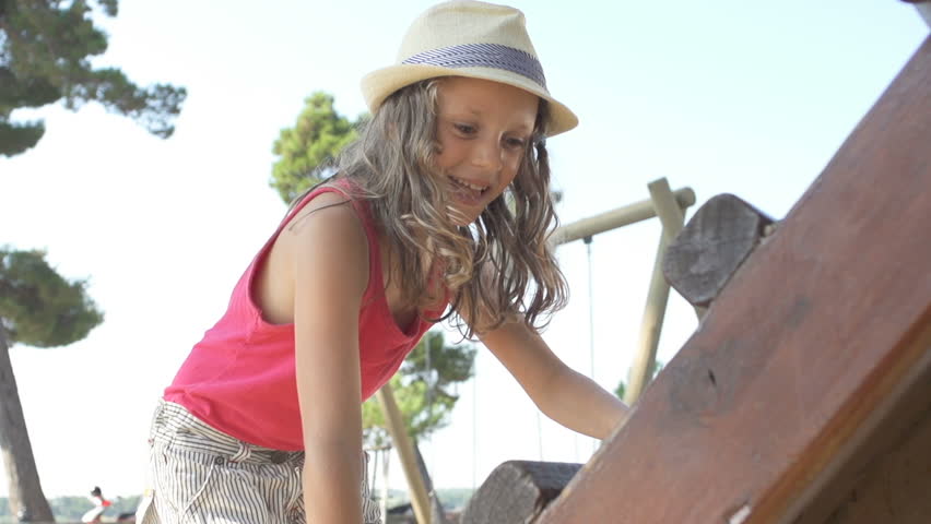 Slow Motion Shot Of A Cute Girl Climbing Up Wooden Ladder. She Looks Into Camera