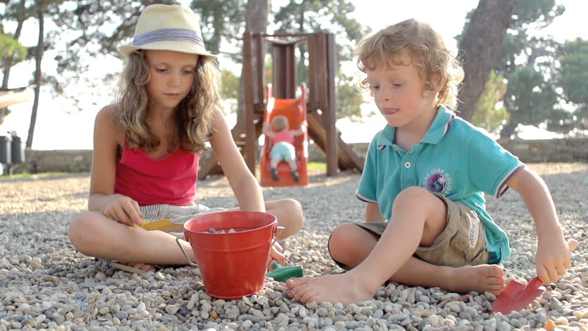 Slow Motion Shot Of A Younger Bother And Older Sister Loading Stones With Spades