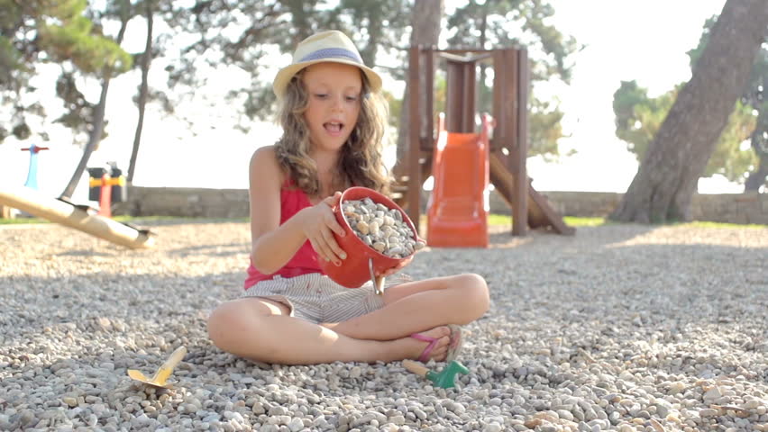 Slow Motion Shot Of A Cute Young Girl Throwing Little Stones Out Of Bucket On