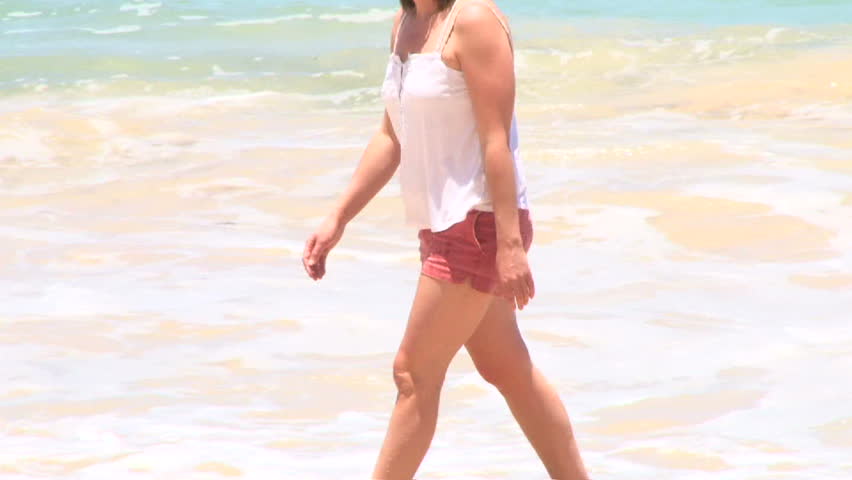 Woman walking on sandy beach on beautiful day in Hawaii.