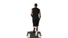 Wide shot of an ethnic man running on a treadmill, as seen from behind on a white background