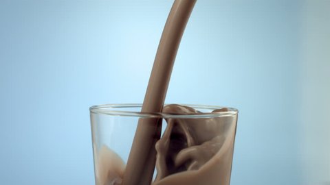 Chocolate milk pouring into glass, slow motion