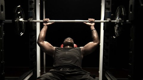 An athlete rests between bench press repetitions and looks into the camera