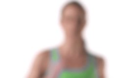 Close up shot of a female running in place on a treadmill, while looking into the camera on a white background