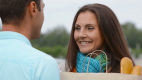 Lovely couple flirting, guy helping young woman to carry her groceries