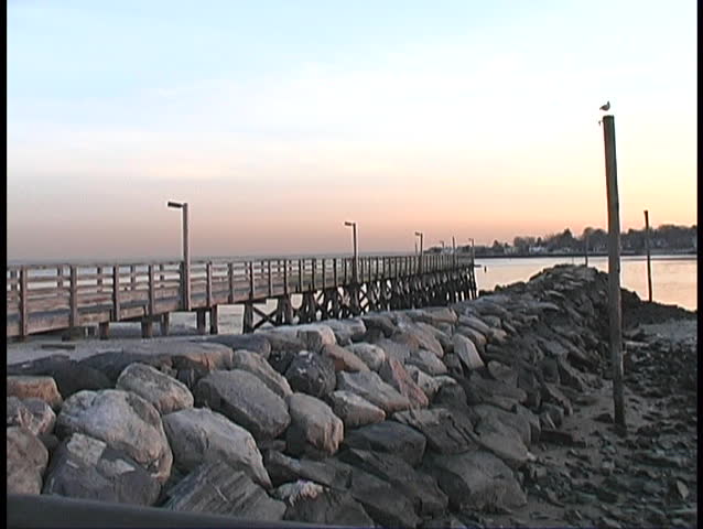 Pier with rock coastline overlooking water with twilight sky