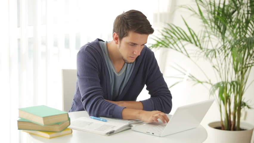 Attractive young man sitting at table with laptop and holding credit card