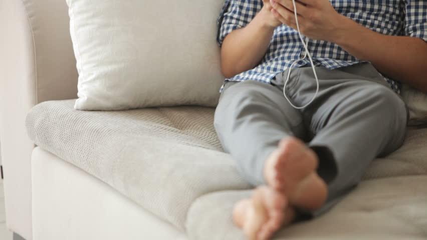 Attractive guy relaxing on sofa and listening to music with earphones