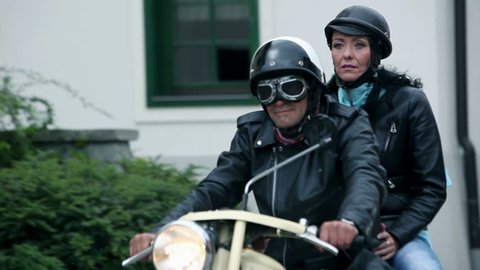 Following middle-aged couple on old motorcycle driving through town