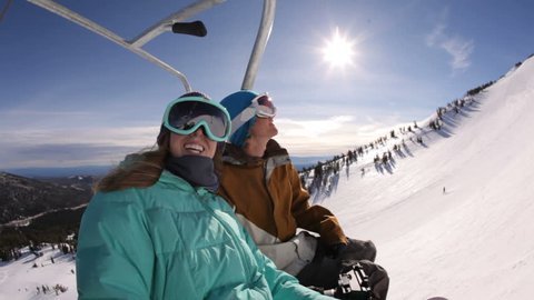 Two snowboarders riding up ski lift