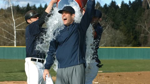 Baseball players pour cooler of water over coach, slow motion