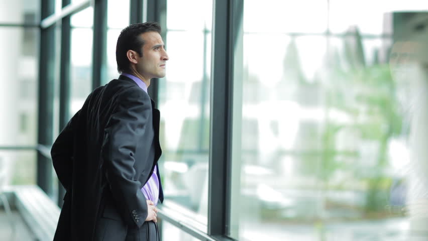 A businessman looks out the window in a contemplative way. Medium shot Royalty-Free Stock Footage #4631570