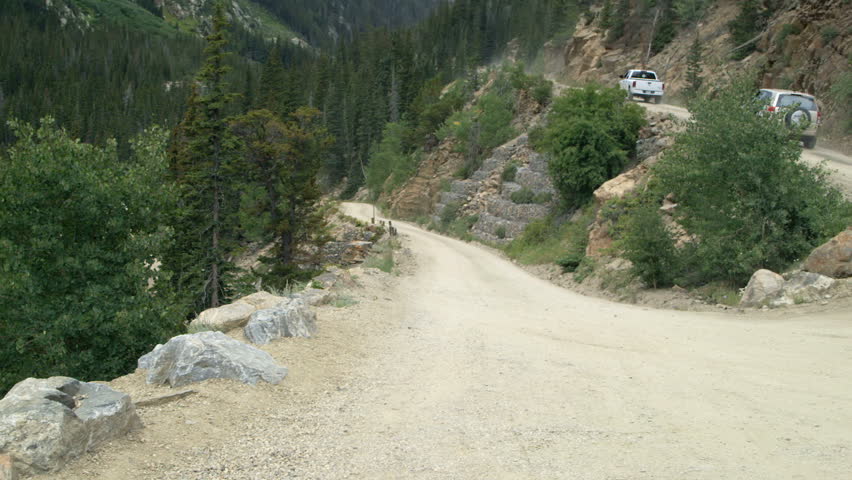 Cars driving up Old Fall River Road near Estes Park Colorado which is a winding one way dirt mountain road.