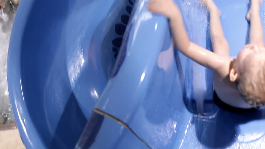 Little boy goes down water slide