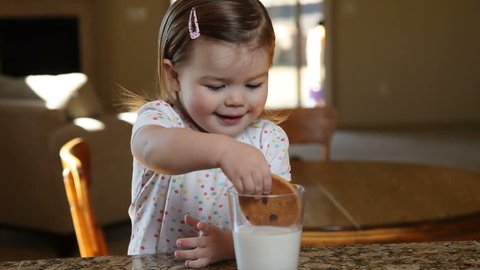 Little girl having milk and cookies