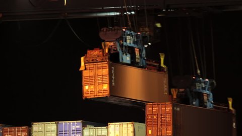 Container ship loading and unloading at night in the port of Hamburg / Germany. A container is moved by a crane across the picture.
