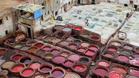 Close overhead view of men stacking dyed garments at a leather tannery in a residential neighborhood in Fez, Morocco