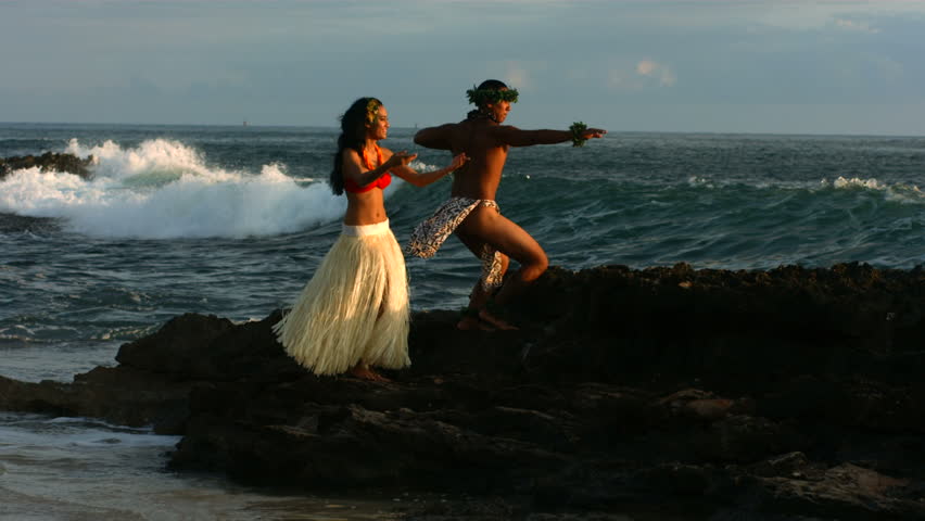 Polynesian dancers perform as waves crash on rocks