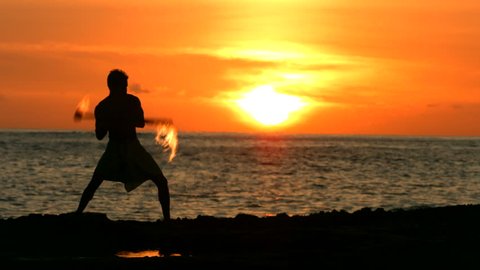 Fire knife dancer performs at sunset