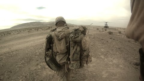 Live action of Marines running in desert for combat loading on a helicopter in the Middle East.Troops running to military helicopter after armed conflict and special operations mission. 