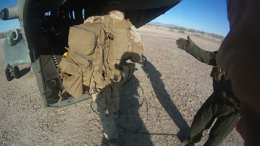 Live action of Marines running in desert for combat loading on a helicopter in the Middle East.Troops running to military helicopter after armed conflict and special operations mission. 