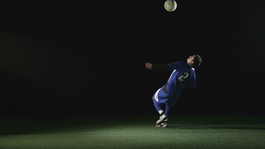 A very good soccer player catches a ball with his chest and then jumps in the air and kicks the ball. Wide slow motion shot.