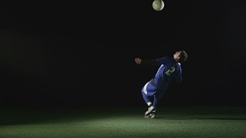 A very good soccer player catches a ball with his chest and then jumps in the air and kicks the ball. Wide slow motion shot.