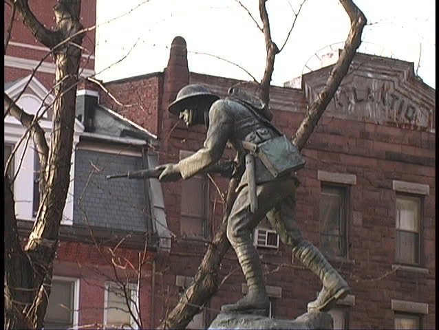 Statue of soldier in front of old brick building with winter trees