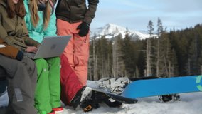 Group of snowboarders watch videos on laptop computer