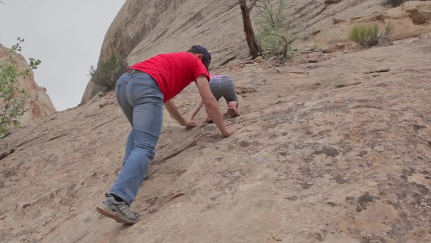 A father teaches his daughter how to climb on desert rocks in Southern Utah