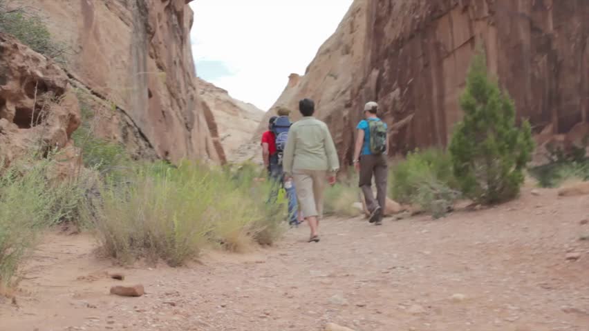 A family walking through a desert slot canyon in Capitol Reef National Park