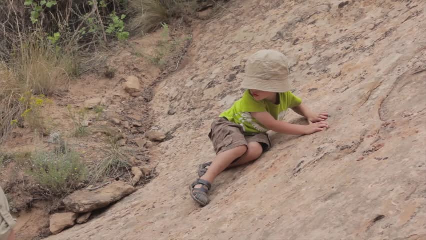 A grandma helping her grandson climb desert rocks in southern utah