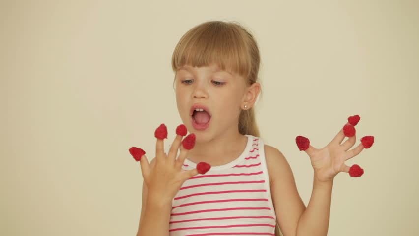 Pretty little girl eating raspberries from top of her fingers