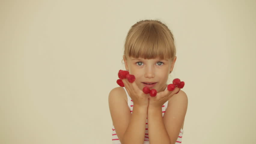 Charming little girl with raspberries on top of her fingers