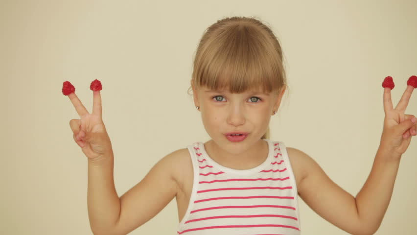 Cheerful little girl with raspberries on top of her fingers
