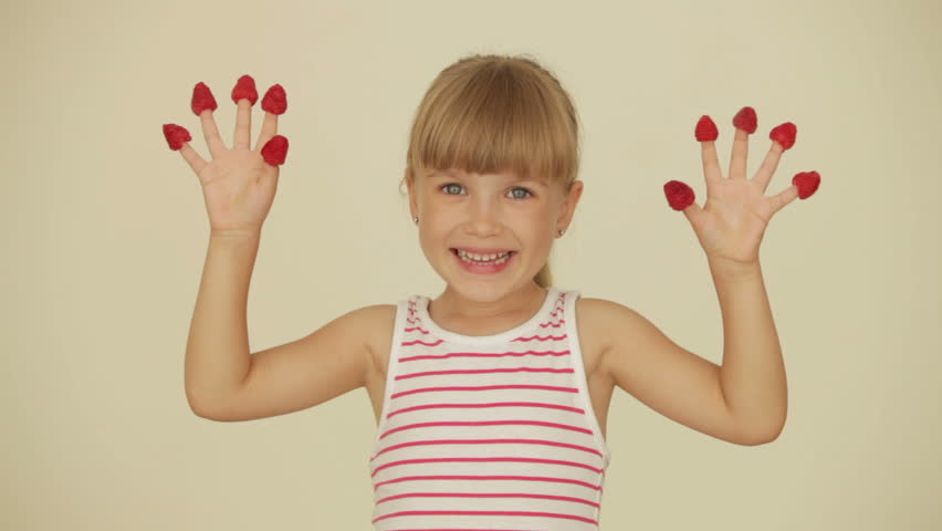 Funny little girl posing with raspberries on top of her fingers