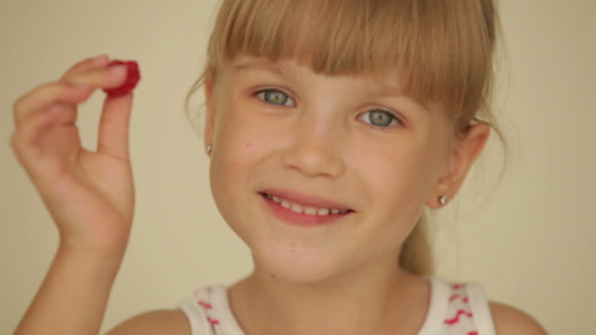 Pretty little girl with raspberries on top of her fingers showing thumb up