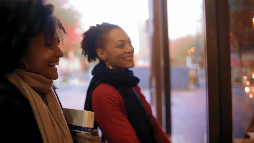 Two young women window shop in a city. Close up shot.