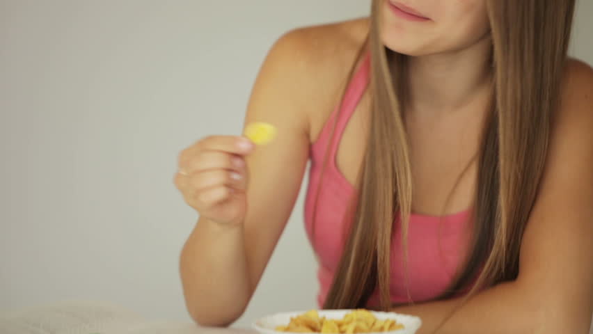 Student girl sitting at table and eating cornflakes