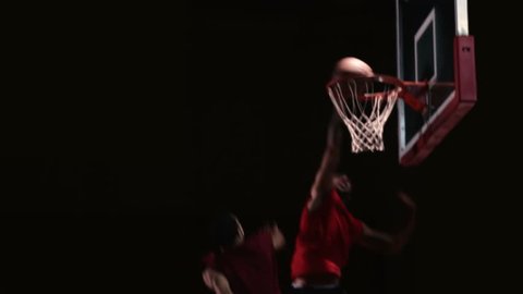 A basketball player goes one on one against a defender and then slam dunks the ball