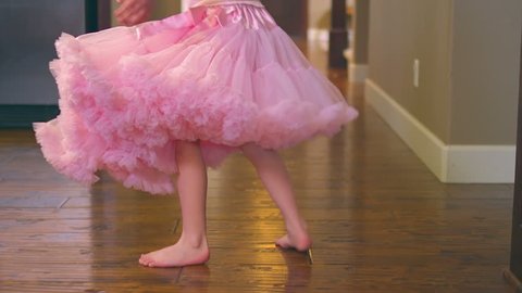 A cute little girl twirls and spins in the kitchen dressed in a leotard. Close up slow motion dolly shot.