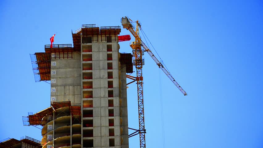 Construction Site, Crane is lifting material at skyscraper building. Clear blue