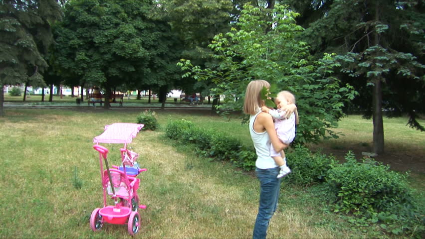 Mother and baby on walk in park. Camera flies 