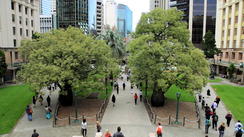 Commuters and pedestrians walk through Anzac Square between skyscrapers in central Brisbane, Queensland, Australia