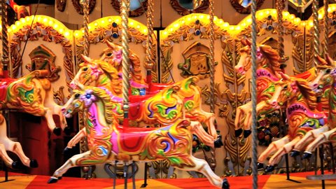 Empty fairground carousel moving with colorful wooden horses, London, United Kingdom