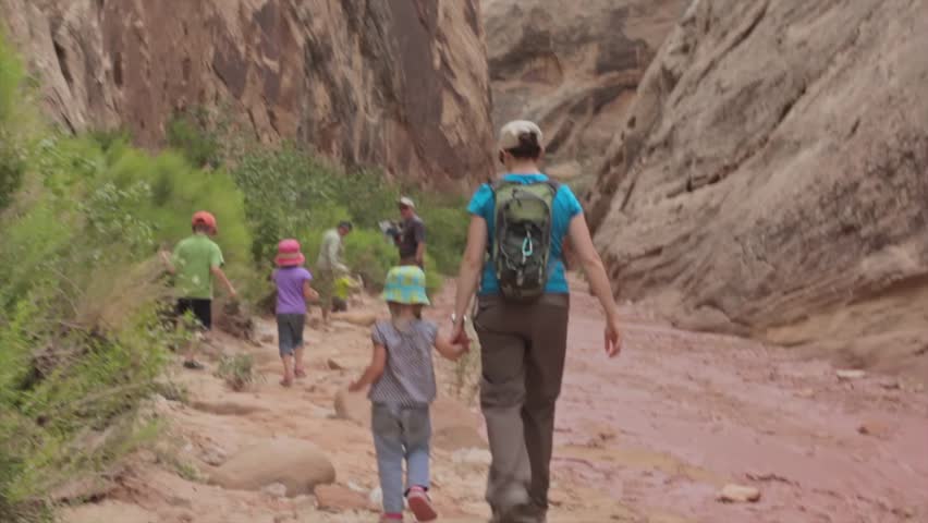 A family hiking in a deep desert slot canyon in Capitol Reef National Park